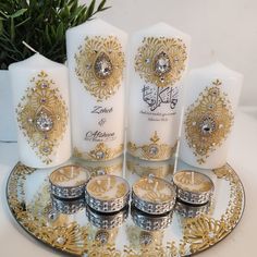 four white candles are sitting on a gold and silver plate with other decorative items around them