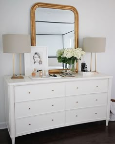 a white dresser with flowers and pictures on it