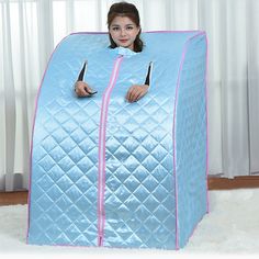 a woman is sitting in a blue and pink portable bed