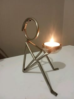 a small metal candle holder sitting on top of a white table next to a wall