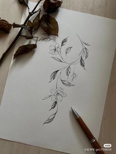 a drawing of flowers on paper next to a pen and some dried up branches with leaves