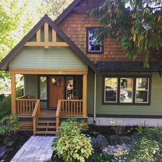 a green house with steps leading to the front door and covered in wood shingles