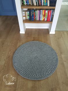 a book shelf filled with lots of books next to a rug on top of a hard wood floor