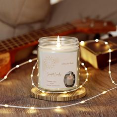 a lit candle sitting on top of a wooden table next to a string of lights