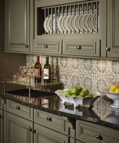 a kitchen with green cabinets and marble counter tops, wine glasses on the cabinet doors