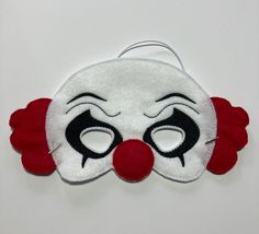 a red and white clown mask with black eyes