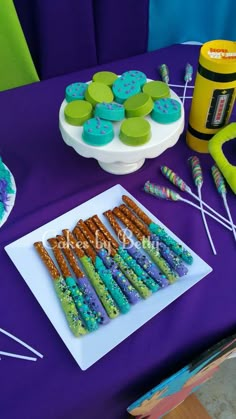 there are many cookies on the table with blue and green icing, including marshmallows