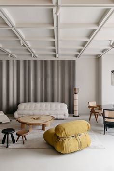 a living room filled with furniture next to a dining table and two chairs in front of a wall