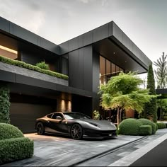 a black sports car parked in front of a modern house with trees and bushes on the side