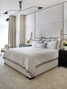 an image of a bed with white sheets and black trim on the headboard in a bedroom