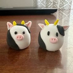 two small cow figurines sitting on top of a wooden table next to each other