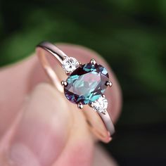 a woman's hand holding an engagement ring with blue and white stones