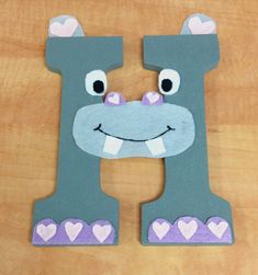 the letter h is made out of felt and has hearts on it's face