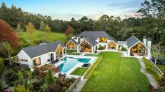 an aerial view of a house with a swimming pool in the foreground and lush green yard