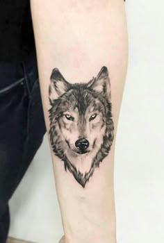 a black and white wolf tattoo on the arm