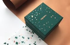 a green box sitting on top of a table next to a piece of wrapping paper