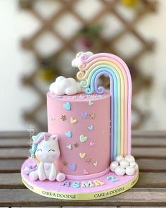 a pink cake decorated with an unicorn and rainbow