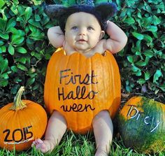 a baby sitting next to three pumpkins with writing on them