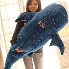 a woman holding a giant stuffed whale in her arms