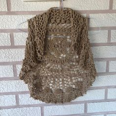 a crocheted sweater hanging on a brick wall