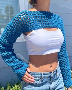 a woman is wearing a blue crochet sweater and jeans with her hands on her hips