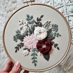 someone is holding up an embroidery hoop with flowers on it