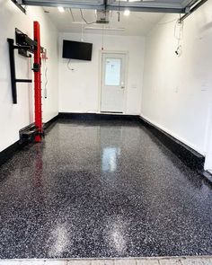 an empty garage with black and white flooring on the walls, television mounted to the wall