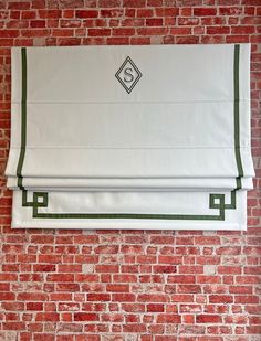 a red brick wall with a white and green roman blind hanging on it's side