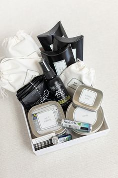 an assortment of personal care items in a tray on a bed with white linens