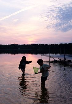 two children playing in the water at sunset