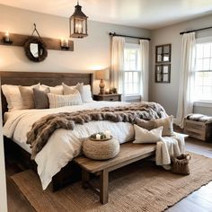 a large bed sitting in a bedroom on top of a wooden floor next to two windows