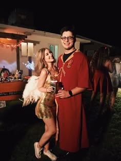 a man and woman dressed in costume standing next to each other on the lawn at night