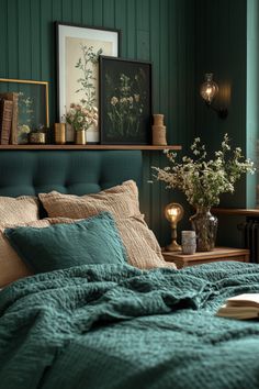 a bed with green sheets and pillows in a bedroom next to a shelf filled with flowers