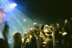 a man playing guitar on stage in front of a crowd at a music concert with bright lights