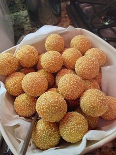 a bowl filled with sesame balls on top of a counter next to a knife and fork