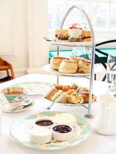 three tiered trays filled with sandwiches and pastries on top of a table