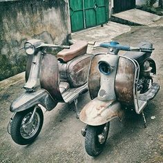 an old scooter parked on the side of a road next to a building