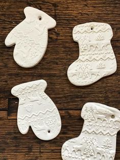 four white ceramic christmas stocking ornaments sitting on top of a wooden table