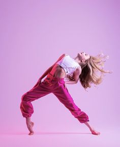 a woman in pink pants and white shirt doing a dance move