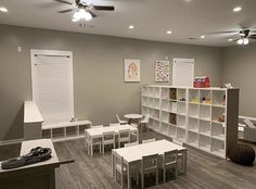 a room with several tables, chairs and bookshelves on the wall in front of them