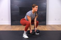 a woman squats with two dumbbells in front of her