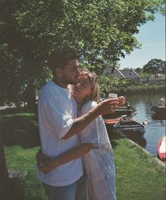 a man and woman standing next to each other in front of a body of water