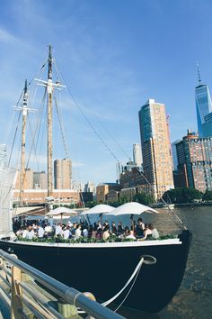 a boat with people sitting on it in the water near tall buildings and skyscrapers