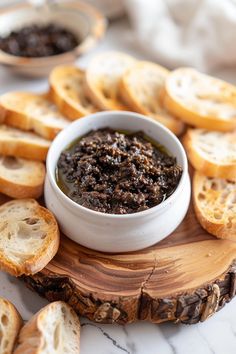 bread slices are arranged around a small bowl of black olive spread on top of them