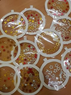 six clear plates with gold and red stars on them sitting on a wooden table top