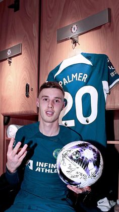 a man holding a soccer ball in front of a locker with his name on it