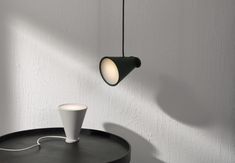 a black table with a white cup on it and a light hanging from the ceiling