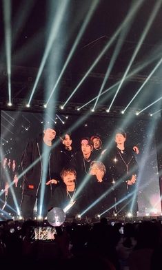 a group of men standing on top of a stage with lights shining in front of them