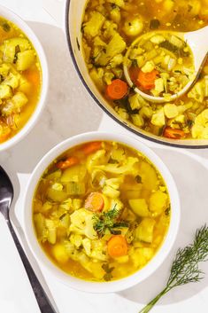 two bowls of vegetable soup with spoons on the side and one bowl filled with vegetables