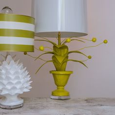 two lamps sitting on top of a wooden table next to a white vase with yellow flowers